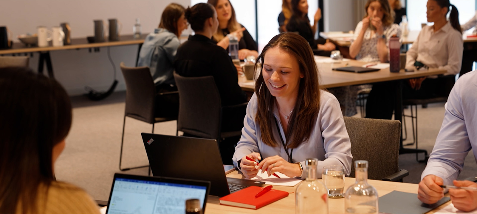 graduate smiling in a Hugh James training session surrounded by peers