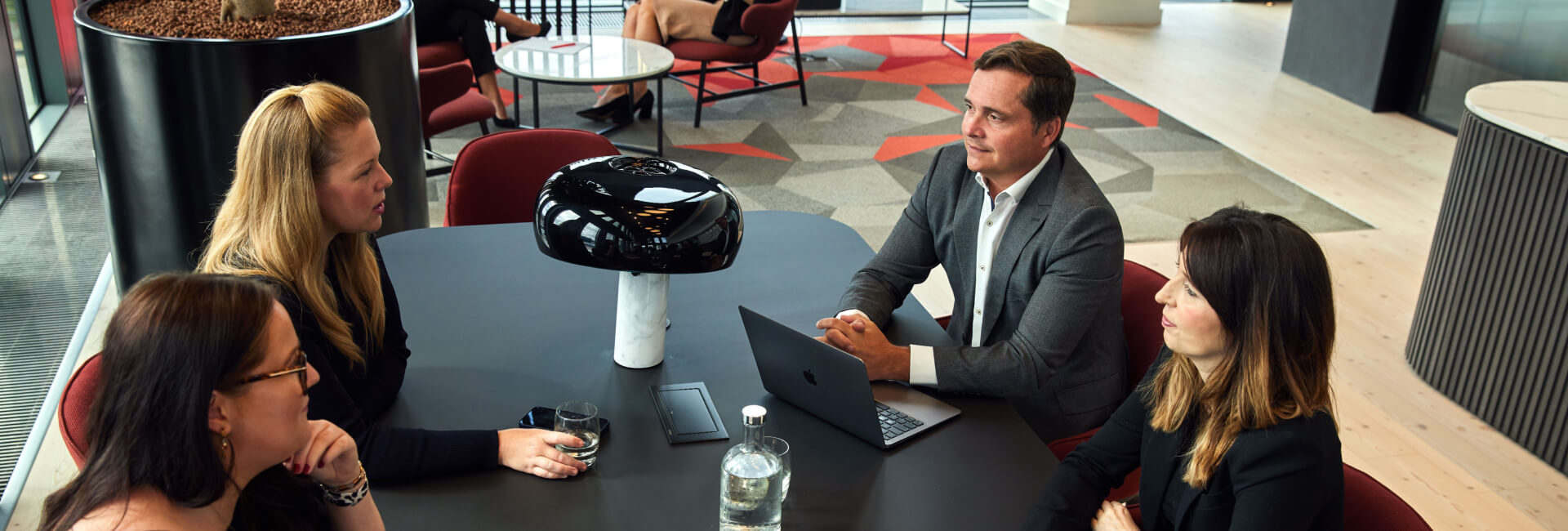 Hugh James Partners meet around a dark table in the Vista client lounge of the Cardiff office